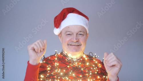 Senior man in red christmas hat dancing celebrating New Year.