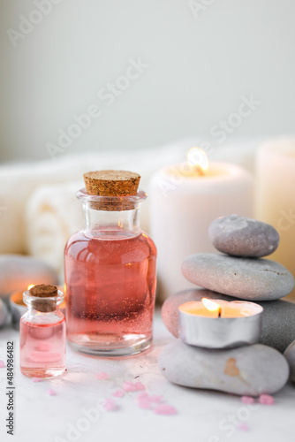 Concept of spa treatment in salon. Natural organic oil  towel  candles as decor. Atmosphere of relax  serenity and pleasure. Anti-stress and detox procedure. Luxury lifestyle. White wooden background