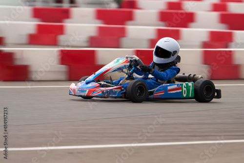 A child is racing on a small racing car on a sports court. Blur in motion. Selective focus.