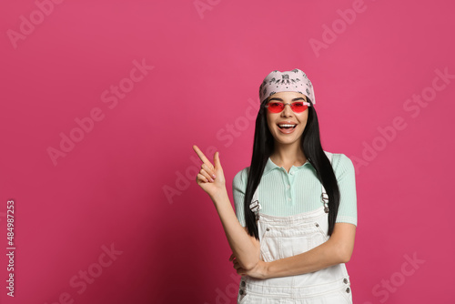 Young woman wearing stylish bandana and sunglasses on pink background, space for text