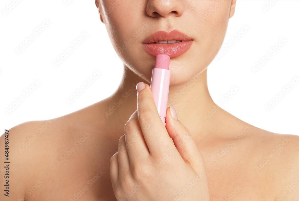 Obraz premium Young woman applying lip balm on white background, closeup