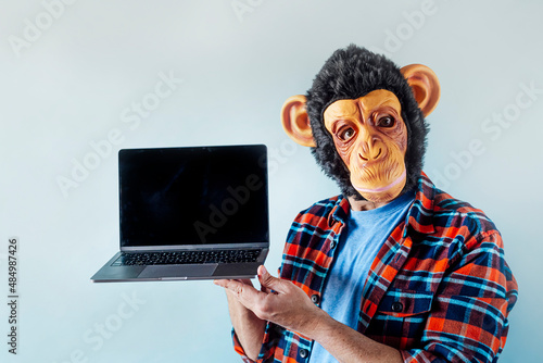 Photography Man wearing monkey mask and using a laptop.