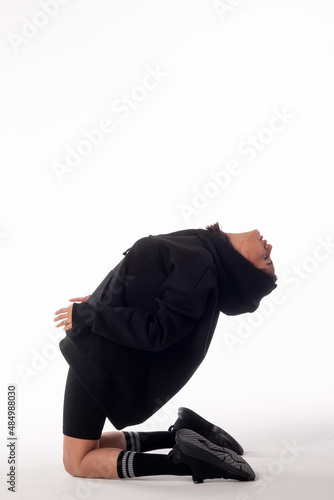 Attractive woman of Latin appearance wears a dark hoodie on a white isolated background. The girl looks sexy and happy. The elegant brunette is wearing a black sweatshirt. All-season clothing