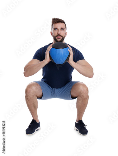 Athletic man doing squats with medicine ball isolated on white