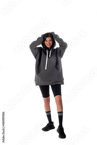 An attractive woman of Latin appearance wears a gray hooded hoodie on a white background. The girl looks sexy and happy. The elegant brunette is wearing a dark sweatshirt. All-season clothing
