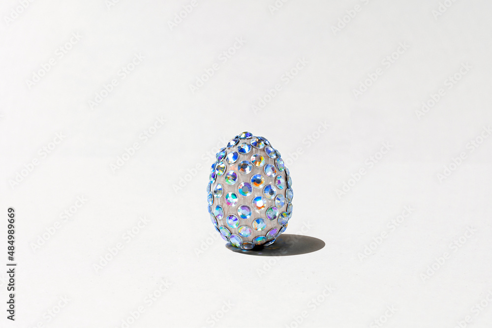 Mock up luxury Easter egg with diamonds on neutral background. Trendy holographic design with rhinestones for party, greeting card or sale. Creative Easter concept. Sunlight, hard shadow Mock up luxury Easter egg with diamonds on neutral background. Trendy holographic design with rhinestones for party, greeting card or sale. Creative Easter concept. Sunlight, hard shadow