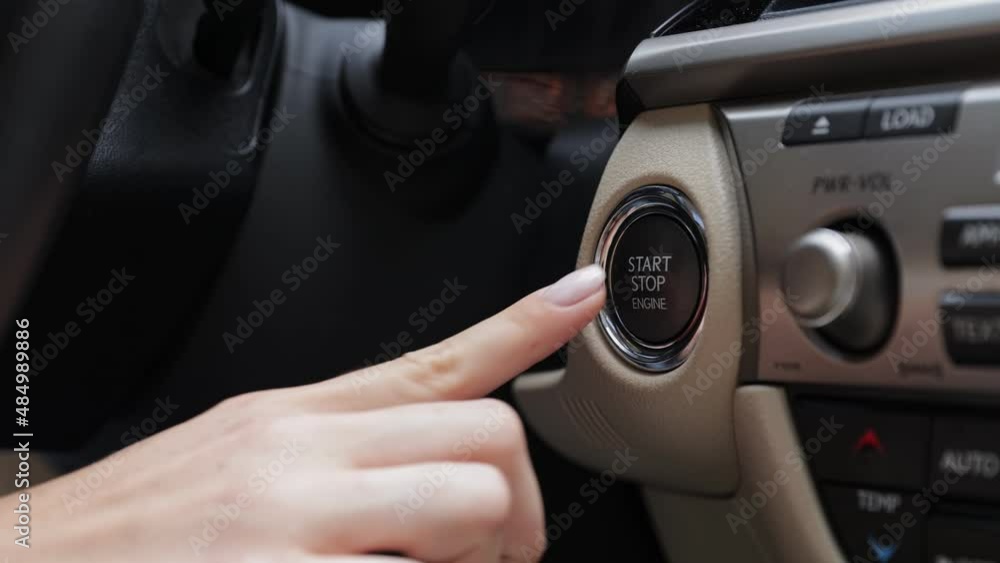 Woman driver pushing a start ignition button switch in the modern luxury car Woman driver pushing a start ignition button switch in the modern luxury car
