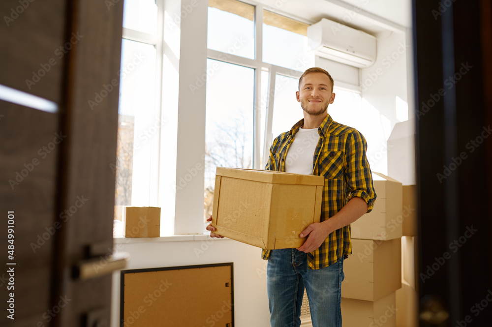 Young man carrying cardboard box during relocation Young man carrying cardboard box during relocation