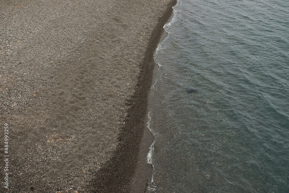 View of the famous black beach of Kamari without tourists in Santorini Greece