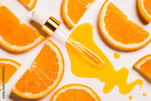 Vitamin C anti aging antioxidant beauty serum or oil drops and dropper on white background and slice of orange fruit natural organic cosmetic concept.
