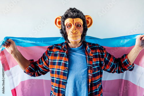 Photography Man in monkey mask holding transgender flag.