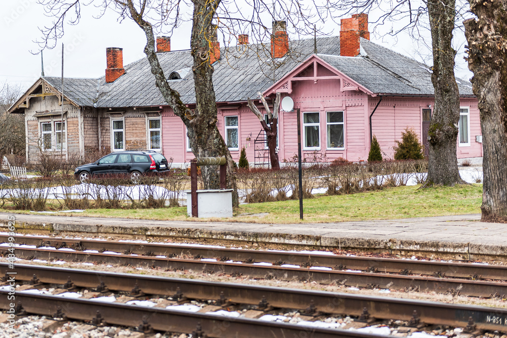 Old historic house, partly pink, partly brown, with lots of chimneys and wood carvings on the railway tracks.