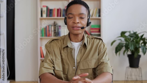 woman sitting at the table having a video call with friends at home. A young Afro-American hotline specialist helps clients remotely at the workplace.