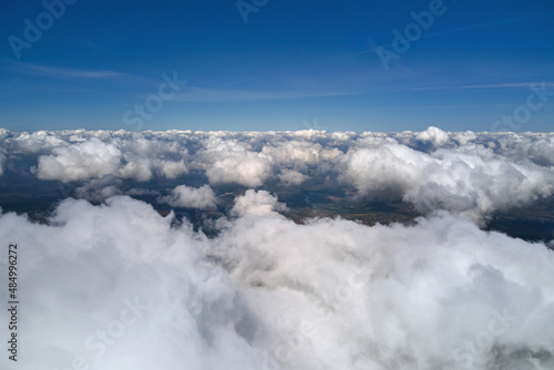 Aerial view from airplane window at high altitude of earth covered with white puffy cumulus clouds