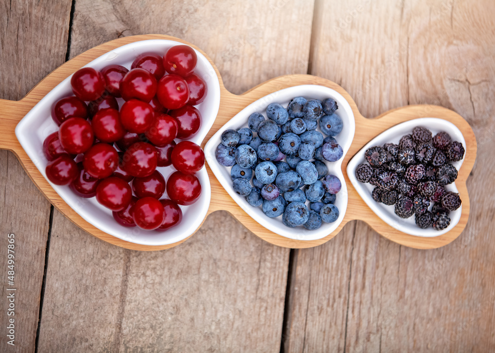 Portion wooden dish on light wooden background top view. Wooden partitioned dish divided into equal 3 section with berries Portion wooden dish on light wooden background top view. Wooden partitioned dish divided into equal 3 section with berries