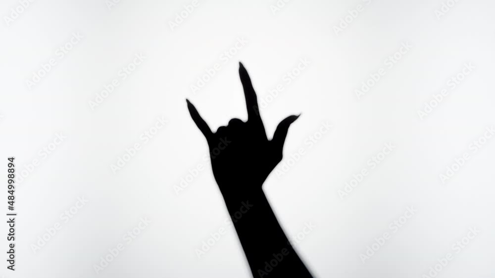 Woman showing rock and roll gesture with fingers isolated on white background. Female person making shadow silhouette with hand close-up. Woman showing rock and roll gesture with fingers isolated on white background. Female person making shadow silhouette with hand close-up.