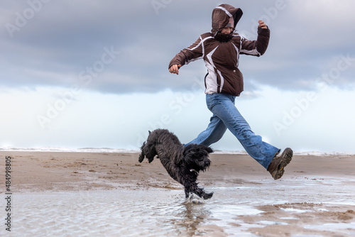 girl and dog running on the beach