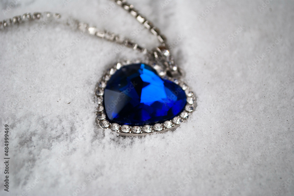 Close-up of the Heart of The Ocean necklace on snow. Titanic necklace. Blue diamond in a heart shape. Diamond necklace. Close-up of the Heart of The Ocean necklace on snow. Titanic necklace. Blue diamond in a heart shape. Diamond necklace.