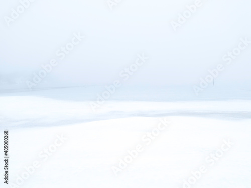 Minimalist winter seascape of the frozen ocean and snowy sky. Soft Zen-like Asian painting style landscape with space for texts and design. © Naya Na