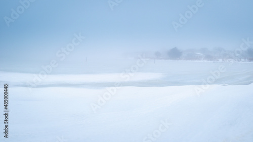 Minimalist winter seascape of the frozen bay covered with snow and ice blocks on Cape Cod. Soft Zen-like Asian painting style landscape with space for texts and design. © Naya Na