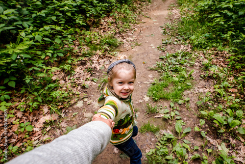 Girl pulling mom in the woods on a hike photo