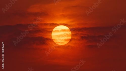 Fotografi Close up view of sunset sun behind clouds like fire ball, telephoto lens shot