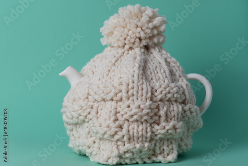 white teapot with a knitted tea cosy