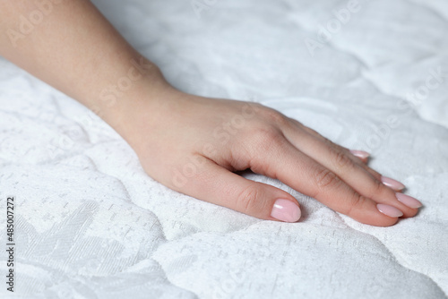 Woman touching soft white mattress, closeup view