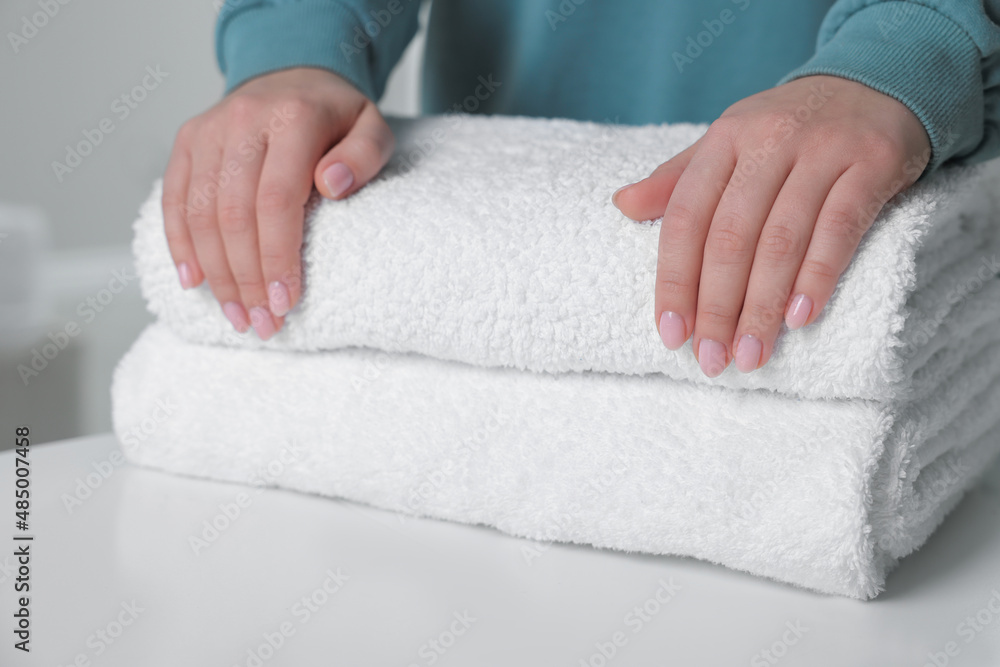 Woman touching soft white towel indoors, closeup Woman touching soft white towel indoors, closeup