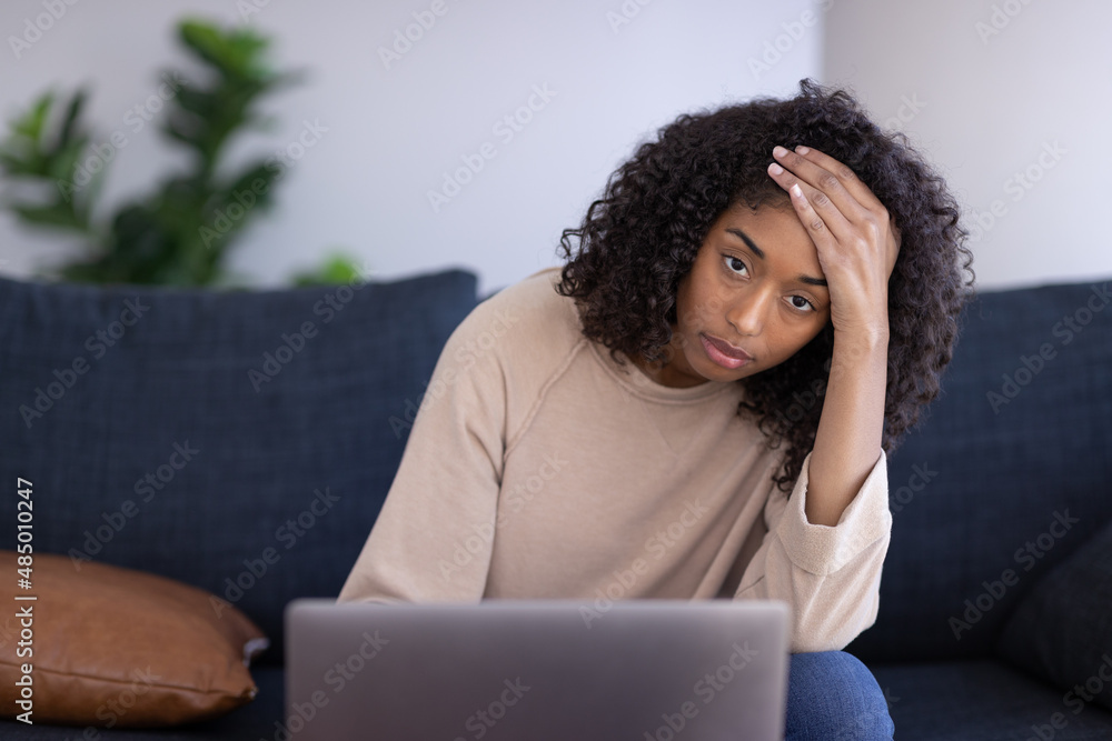 Young black woman using laptop computer at home sitting on a couch Young black woman using laptop computer at home sitting on a couch