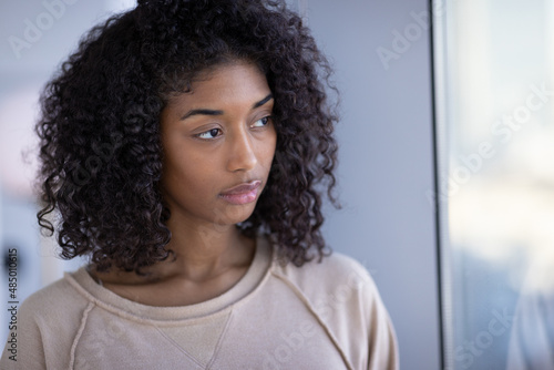 Young black woman at home sad depressed serious face portrait standing by a window