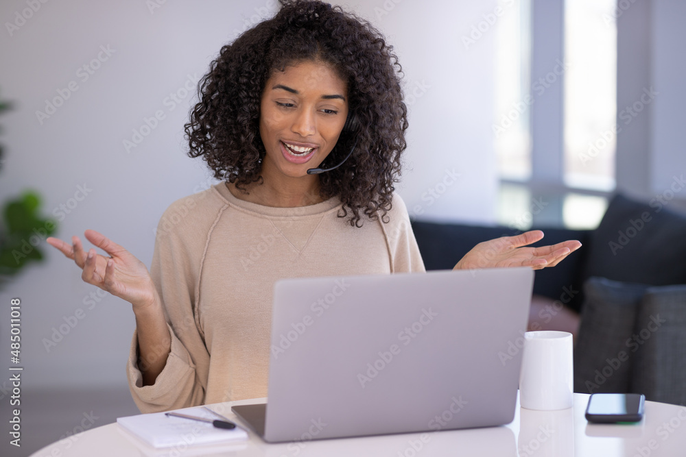 Young black woman at home remote working on laptop computer talking to her colleague Young black woman at home remote working on laptop computer talking to her colleague