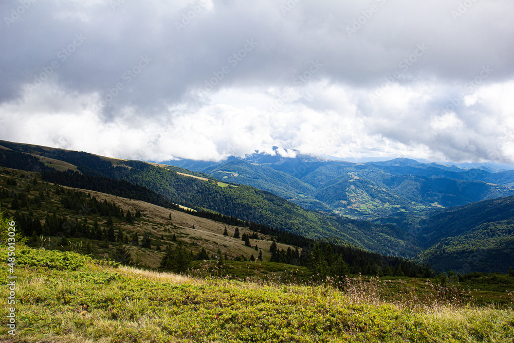 Fototapeta premium View of green and blue mountains. Background with white clouds on a sunny summer day. Concept of European mountains and traveling