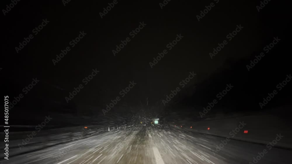 Vehicle driving at winter night road while snow flying towards in windshield. POV shot. Vehicle driving at winter night road while snow flying towards in windshield. POV shot.