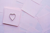 un dije de corazón de metal sobre papelitos de color rosado para san valentín y día del amor y la amistad, limpio y con espacio para texto
