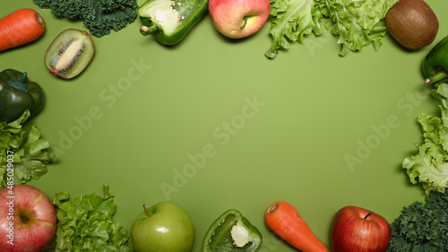 Assorted raw organic vegetables and fruits isolated on green background. Flat lay.
