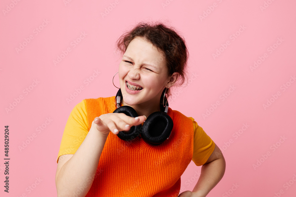 Obraz premium pretty girl listening to music with headphones orange sweater emotions fun cropped view unaltered
