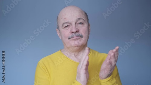Senior man clapping and applauding with disbelief at his face. Studio shot
