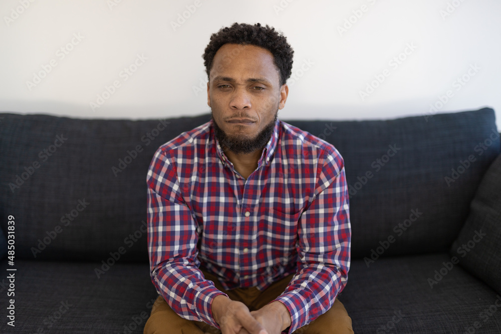 Black man at home sitting on a couch feeling sad and depressed Black man at home sitting on a couch feeling sad and depressed