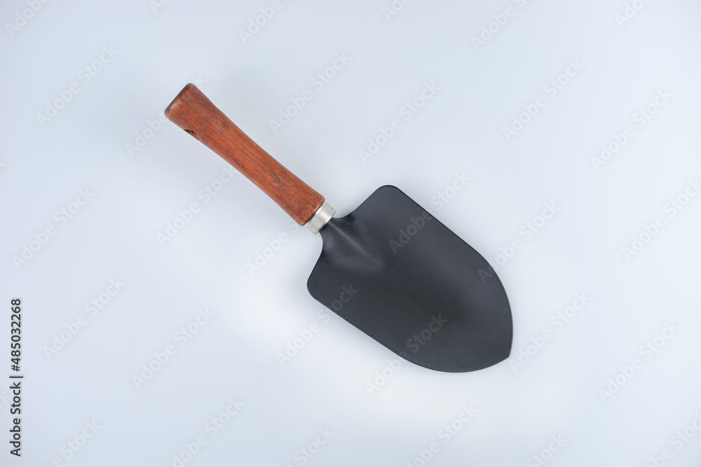 A black shovel with wooden handle on white background. A black shovel with wooden handle on white background.
