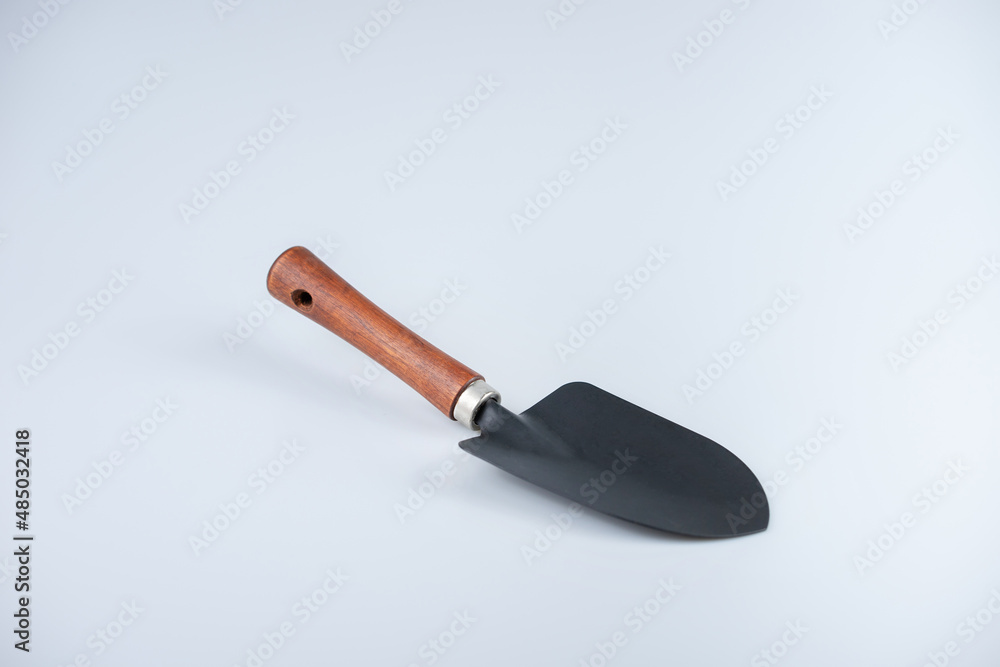 Fototapeta premium A black shovel with wooden handle on white background.