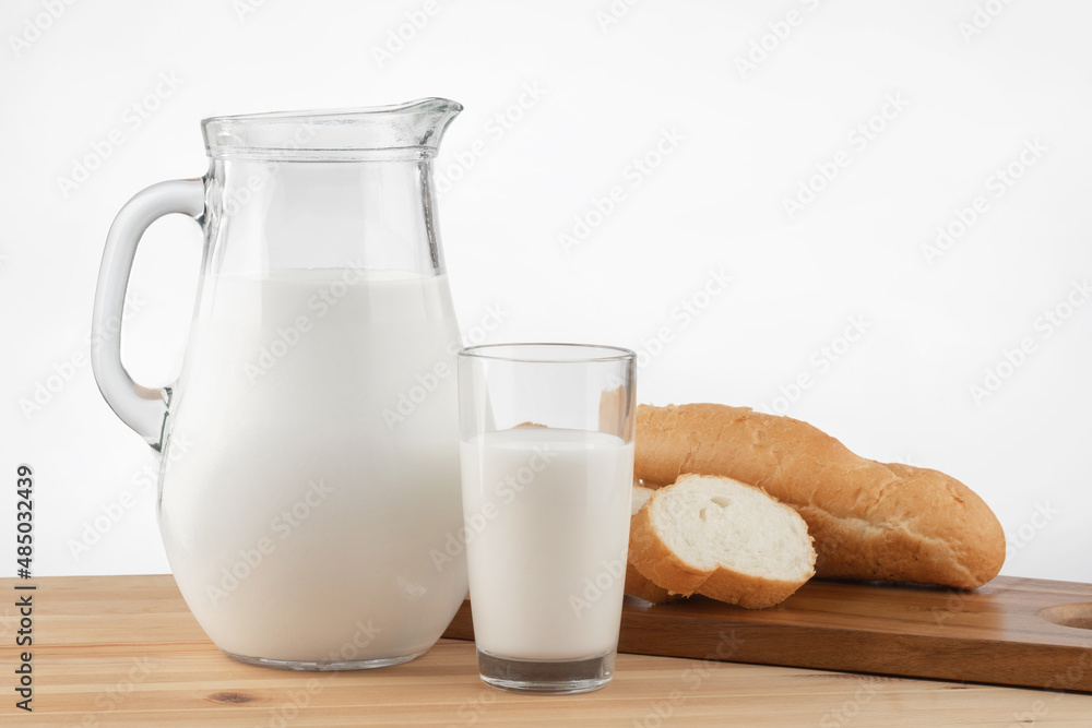 a glass jug with milk and a glass stand on a wooden table with a linen tablecloth a glass jug with milk and a glass stand on a wooden table with a linen tablecloth