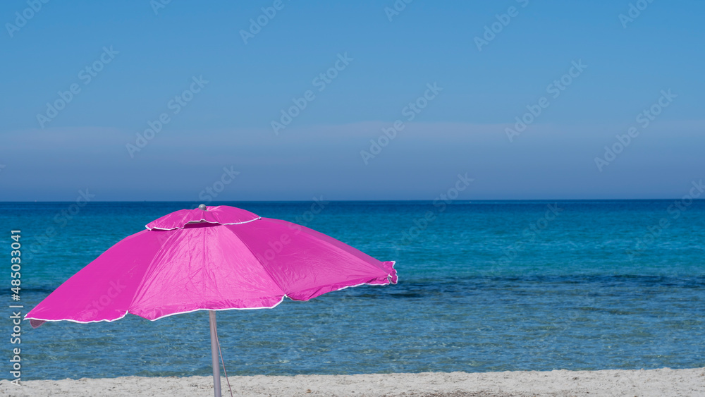 Isolated fuchsia or pink beach umbrella. Blue sky. Relaxing context. Summer holidays at the sea. General contest and location. Turquoise sea and white beach in the background
