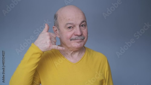Senior hispanic man show sight call me with fingers