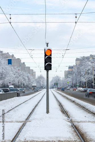 Traffic light with a red signal in the center of the street between the tramways photo