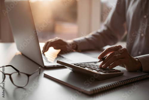 Принти на полотні Man accountant using calculator and laptop computer in office, businessman working at home, finance and accounting concept