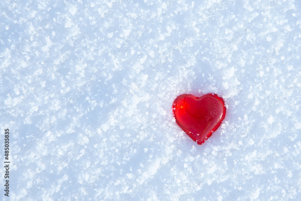 Close-up of small red heart on white blue real snow background. Close-up of small red heart on white blue real snow background.