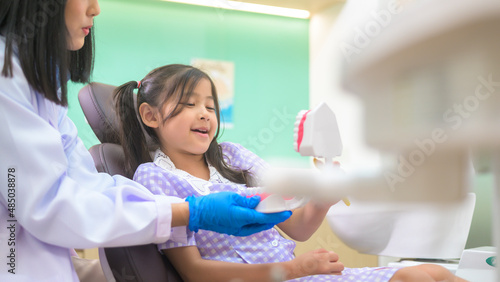Female dentist demonstrating how to brush teeth to a little girl in dental clinic  teeth check-up and Healthy teeth concept