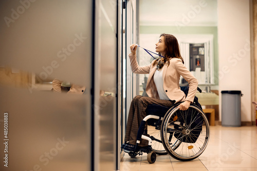 Young handicapped businesswoman uses access card to enter the office. photo