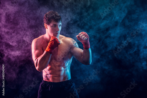 Half length of shirtless boxer fighter who preparing for fight on smoke background. Sport concept © zamuruev